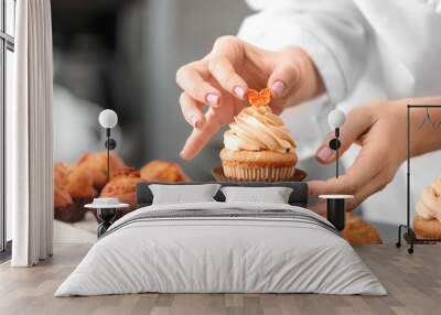 Woman decorating tasty cupcake at table Wall mural