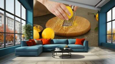 Woman grating zest of lemon on kitchen table Wall mural