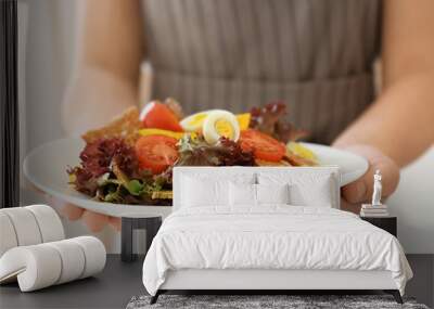 Woman holding salad with quail eggs and tomatoes on white plate Wall mural