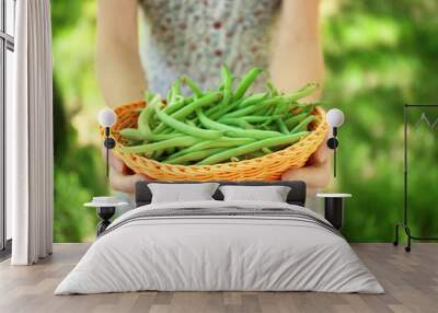 Woman holding wicker basket with raw fresh organic green beans outdoors Wall mural