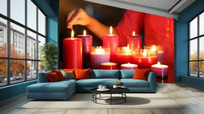 Woman lights candles on bright background Wall mural