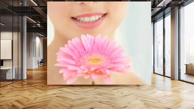 Woman with natural makeup and flower near face on blurred background Wall mural