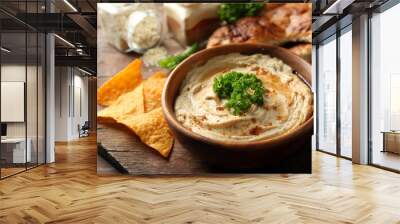 Wooden bowl of tasty hummus with chips and parsley on table Wall mural