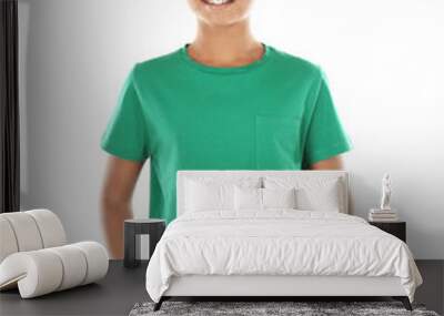 Young African American boy in blank green t-shirt standing on white background Wall mural