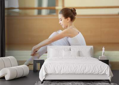 Young beautiful ballerina tying point shoes on floor Wall mural