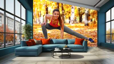 Young beautiful woman doing sport exercises in autumn park Wall mural