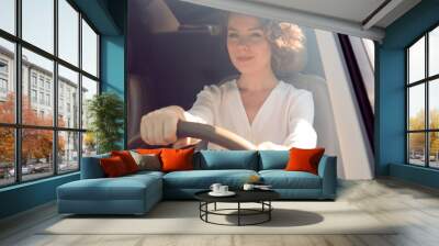 Young businesswoman driving a car, view from outside through windscreen Wall mural