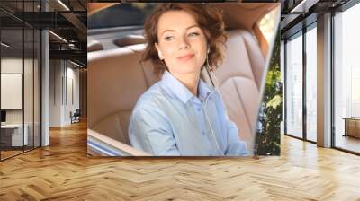 Young businesswoman listening to music on back seat of a car Wall mural