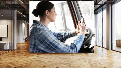 Young female driver sitting in cabin of big modern truck Wall mural