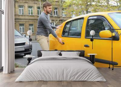 Young man getting into taxi car Wall mural