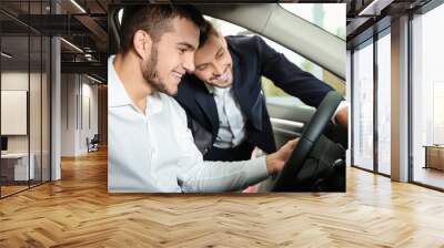 Young man sitting inside of new car at dealership centre Wall mural