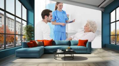 Young man talking with grandmother and nurse Wall mural