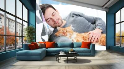 Young man with fluffy cat lying on a sofa Wall mural