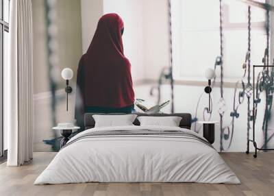 Young Muslim woman praying, indoors Wall mural