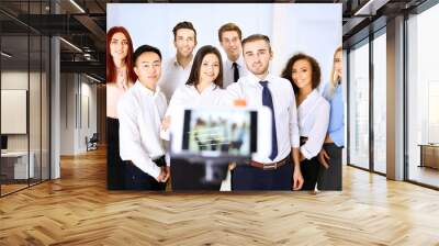 Young people making group photo with smart phone in office Wall mural