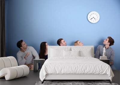 Young people sitting on a chairs and looking at the clock in blue hall Wall mural