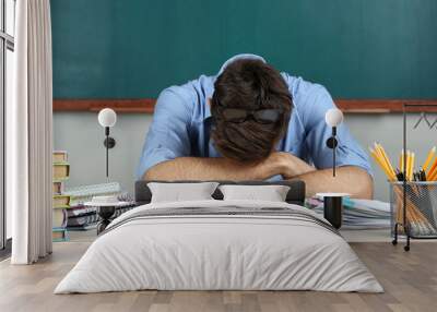 Young teacher sitting in school classroom Wall mural