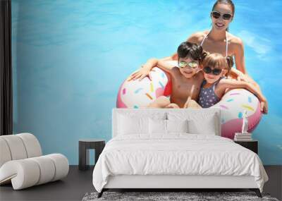 Young woman and her children with inflatable donut in swimming pool Wall mural