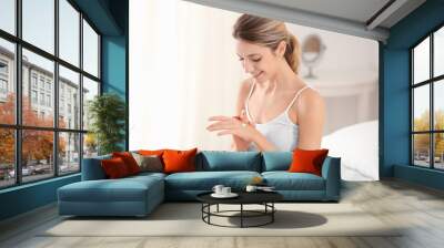 Young woman applying hand cream at home Wall mural