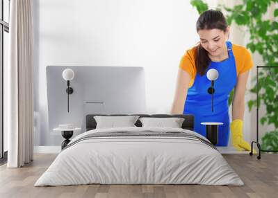 Young woman cleaning workplace with computer monitor in the office Wall mural