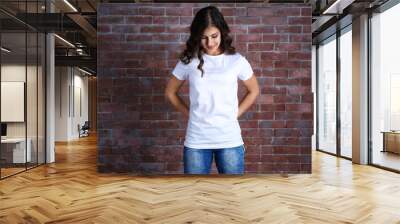 young woman in blank white t-shirt standing against brick wall Wall mural