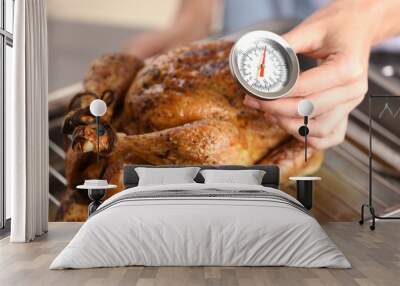 young woman measuring temperature of whole roasted turkey with meat thermometer Wall mural