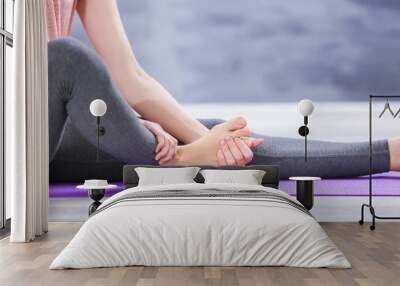 Young woman suffering from pain in foot while sitting on stretching mat, close up Wall mural