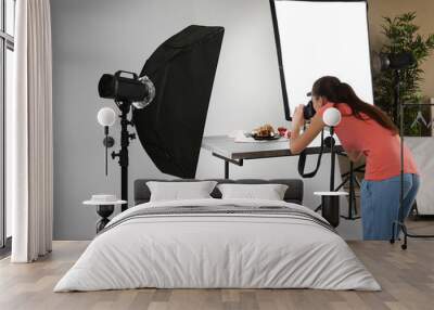 young woman taking pictures of food in professional photo studio Wall mural