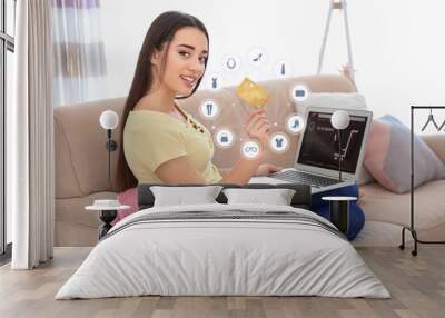 Young woman with credit card using laptop for online shopping at home Wall mural