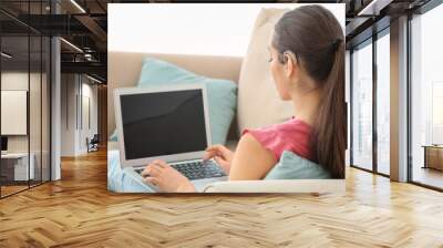 Young woman with hearing aid using laptop indoors Wall mural