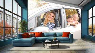 Young woman with her little children in car Wall mural