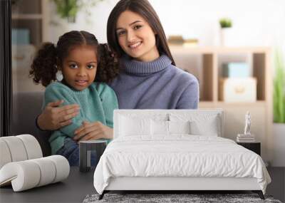 Young woman with little African-American girl indoors. Child adoption Wall mural