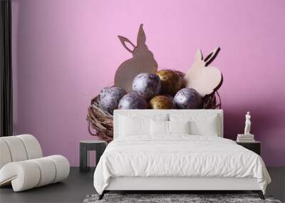 Easter concept - two rabbits in a nest with chocolate eggs against pink background. Horizontal image Wall mural