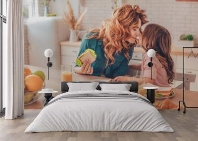 daughter and mother having breakfast and touching noses on the domestic kitchen Wall mural