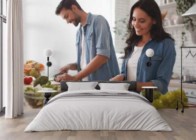 smiling wife and husband cooking dinner in the kitchen together Wall mural