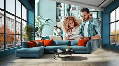 Young businessman and businesswoman making notes in notebook in cafe Wall mural