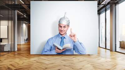 Funny happy man in an aluminum foil hat holds a book and preaches. Concept art phobias Wall mural