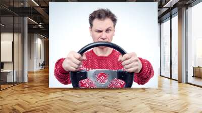 Man in red sweater driving a car with a steering wheel, drive concept  Wall mural