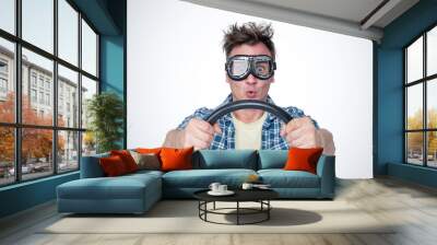 Surprised man in plaid shirt and stylish goggles with steering wheel, front view. Car driver concept Wall mural