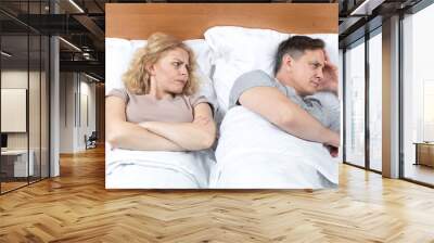 Two in bed, a woman looks with suspicion at a man who has turned away in the other direction. Relationship concept Wall mural