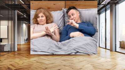 Two people in bed, a begging man shows his fingers to a woman who ignores him how much he needs. Relationship concept Wall mural