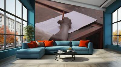 african education - close up of a school kid sitting inside a classroom, holding a pencil, indoors on a sunny day Wall mural