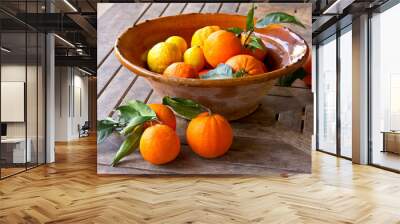 Fresh oranges and lemons with green leaves in a rustic bowl on a wooden table, Majorca or Mallorca. Wall mural