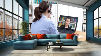 Rear view of a woman in a blue blouse with headset and laptop, having a live video call with her friendly attorney, solicitor or lawyer, online legal advice concept Wall mural