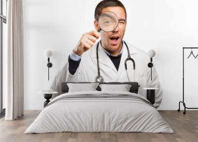 Surprised doctor using a magnifying glass against white background Wall mural