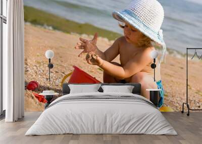 little girl in the bonnet plaing with sand, childhood Wall mural