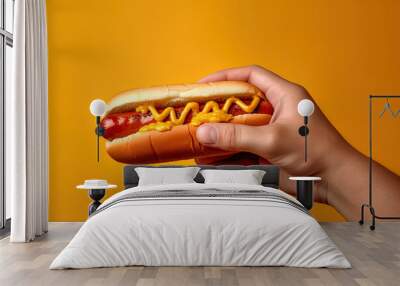 Hand holding tasty hot dog on a yellow background Wall mural