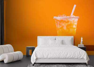 Orange color drink in a plastic cup isolated on a orange color background. Take away drinks concept with copy space Wall mural