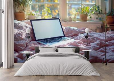 Laptop with blank screen on pink blanket on bed with window and plants in background Wall mural