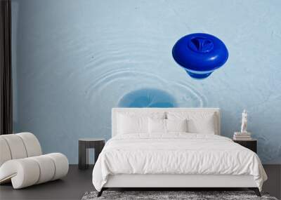 Blue plastic chlorine dispenser floating on the surface of water in home garden swimming pool. Wall mural